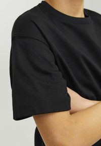 Svart t-shirt med kort ärm i mjuk bomull, med en klassisk rund halsringning och synliga sömnadsdetaljer.