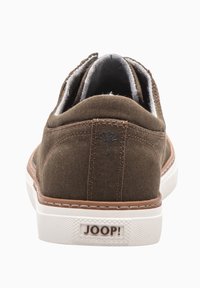 Brown textile sneaker with a tan sole, white accents, and a logo patch. Features a textured upper and a canvas design with contrasting lining.