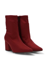 Botas de tobillo rojas hechas de tela suave, con punta afilada y tacón cuadrado. Cuentan con un zipper lateral para ponérselas fácilmente.