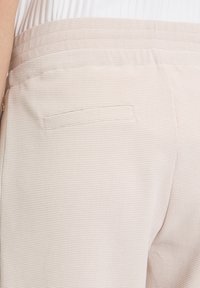 Beige karierte Stoffhose mit einfacher Gesäßtasche und glattem Bund, entworfen für eine taillierte Passform.