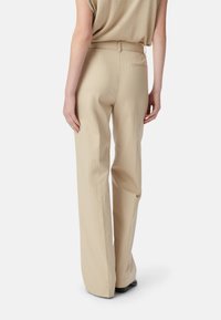 Beige broek met streepmotief en een getailleerde pasvorm, met een platte voorkant, achterzak en een gladde textuur. Effen zoomafwerking.