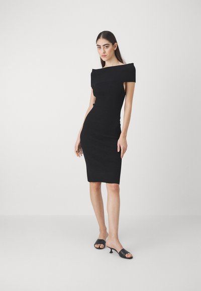 Rochie neagră ajustată cu un design off-the-shoulder. Prezintă un tiv până la genunchi și o textură netedă. Pur și simplu cu sandale cu toc negru.