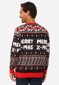 Crni božićni džemper s crvenim i bijelim uzorcima štapića slatkiša, natpisom "SRETAN BOŽIĆ" i rebrastim crvenim manšetama i rubom. Mekana pletena tekstura.