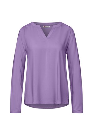 Blusa a maniche lunghe di colore lavanda con scollatura a V e orlo leggermente curvo. Realizzata in tessuto liscio con una leggera lucentezza e dettagli arricciati sulle spalle.