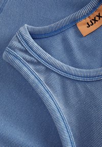 Modré oblečení skládající se ze dvou kusů látky. Jedna část je jednobarevná modrá a druhá má tenké horizontální pruhy. Viditelné švy a štítek.