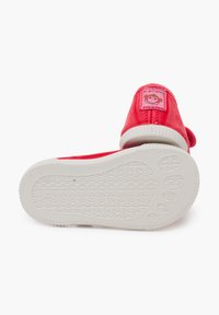 Scarpe in tessuto rosa con suola in gomma bianca. Presentano una piccola toppa ricamata con un design di scimmia sul lato e una suola testurizzata.