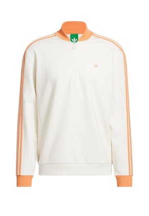 Jersey blanco con detalles naranjas, cuello con cremallera hasta la mitad y tres franjas naranjas a lo largo de las mangas. Presenta un pequeño logo en el pecho.