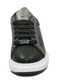 Sneaker nera in pelle con un pannello grigio texturizzato, lacci neri piatti, logo sulla linguetta e suola in gomma bianca.