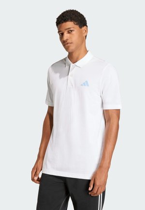 Mann trägt ein weißes kurzärmeliges Poloshirt mit hellblauem Logo auf der Brust und schwarze Hose mit weißen Streifen.