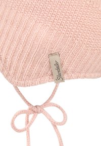 Light pink knit baby bonnet with ribbed edge, tied strap bow, and a beige fabric label with "Sterntaler" text.