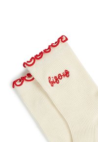 Kerman nauhasukat, joissa on punaiset röyhelöreunat ja punaisella brodeerattu sana "lifeous" ylhäällä.