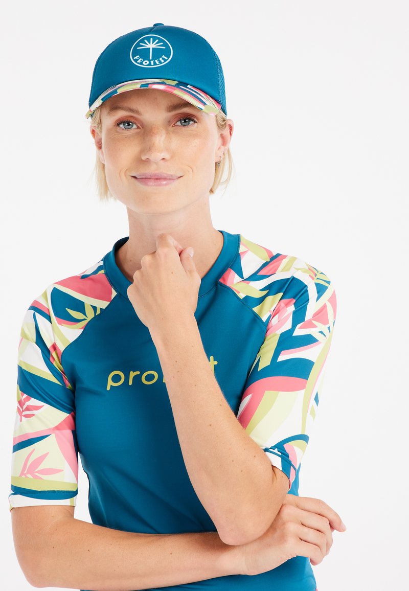 Teal rash guard met kleurrijk tropisch patroon op de mouwen; ronde PROTEST logo pet; gladde stof, korte mouwen, relaxte pasvorm.