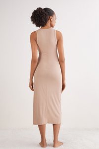 Vestido midi de canalé, sin mangas, ajustado en color beige claro. Presenta un escote redondo y un diseño sin costuras, llegando a la mitad de la pantorrilla. Textura suave.