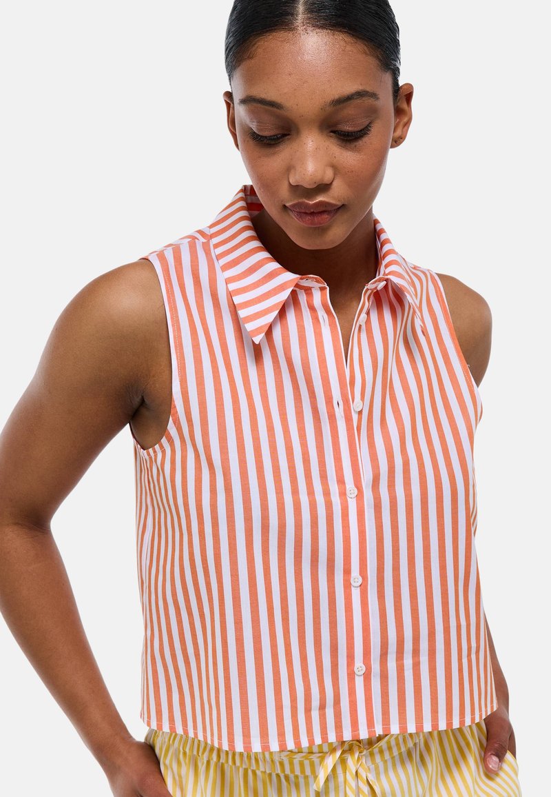 Chemise sans manches à col, à rayures verticales orange et blanches, avec des boutons sur le devant et une coupe courte. Matériau en coton doux.