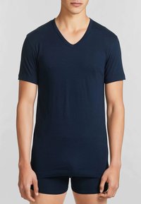 T-shirt blu marino a V in tessuto morbido, con maniche corte e vestibilità rilassata. Abbinato a pantaloni corti scuri per un look coeso.