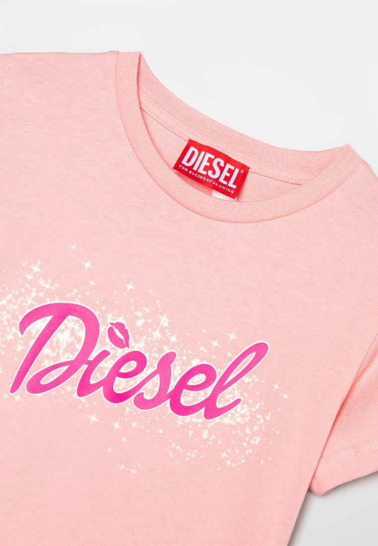 T-shirt di cotone rosa con un grande logo glitterato "Diesel" in rosa e bianco, con un accento a forma di bacio sopra la lettera "i".