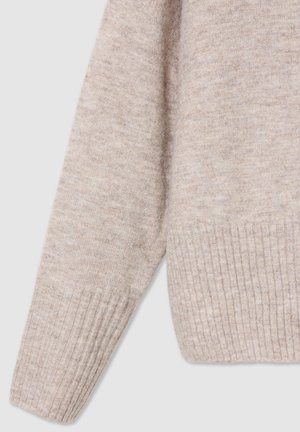 Jasno beżowy sweter z dzianiny, z prążkowanym dołem i mankietami, o miękkiej teksturze i luźnym kroju. Materiał wydaje się lekko melanżowy.