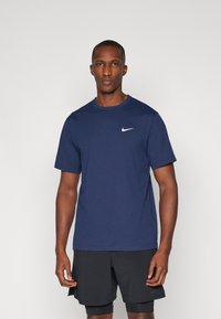 Mørkeblå Nike t-skjorte laget av mykt stoff, med rund hals, korte ermer og en liten hvit logo på venstre bryst.
