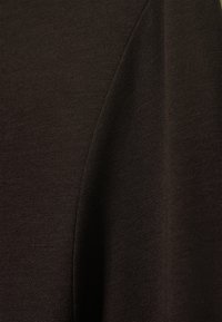 Σκούρο καφέ ύφασμα με λεπτή ραβδωτή υφή, παρουσιάζοντας ομαλές γραμμές και ραφές με ένα αεροδυναμικό, γραμμικό αισθητικό αποτέλεσμα.