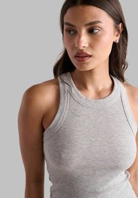 Canotta grigia a coste con design aderente e senza maniche, caratterizzata da un collo rotondo e una texture liscia.
