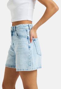 Lichtblauwe denim shorts met een hoge tailleband, voor- en achterzakken, en een licht vervaagde structuur. De zoom is recht afgesneden.