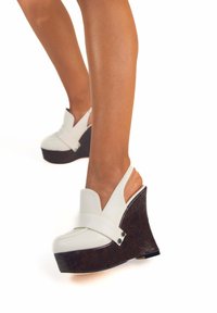 Wedge in pelle bianca con piattaforma, tacco curvo simile al legno scuro e punta arrotondata. Presenta una fascia anteriore per una vestibilità sicura.