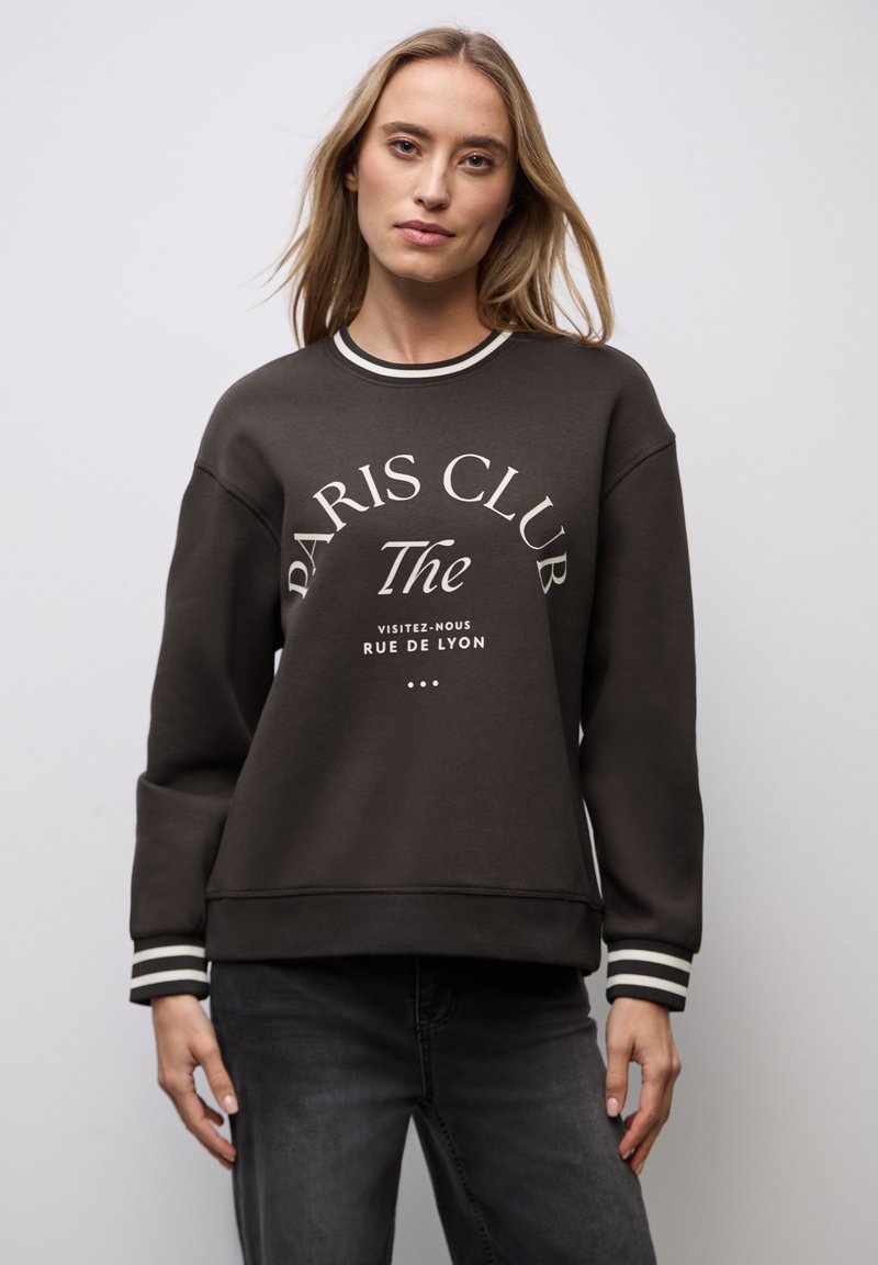 Sweatshirt gris foncé avec lettres blanches, détails côtelés au cou et aux poignets, et coupe ample. Le design présente "Paris Club" de manière centrale.