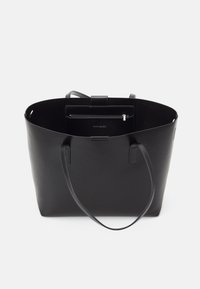 Sac fourre-tout noir avec une texture lisse, une forme arrondie, de longues poignées et une poche intérieure zippée. Design minimaliste avec un logo de marque subtil.