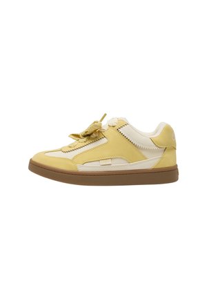 Niedriger Sneaker aus cremefarbenem und gelbem Leder mit dicken flachen gelben Schnürsenkeln und brauner Gummisohle, von der Außenseite betrachtet.