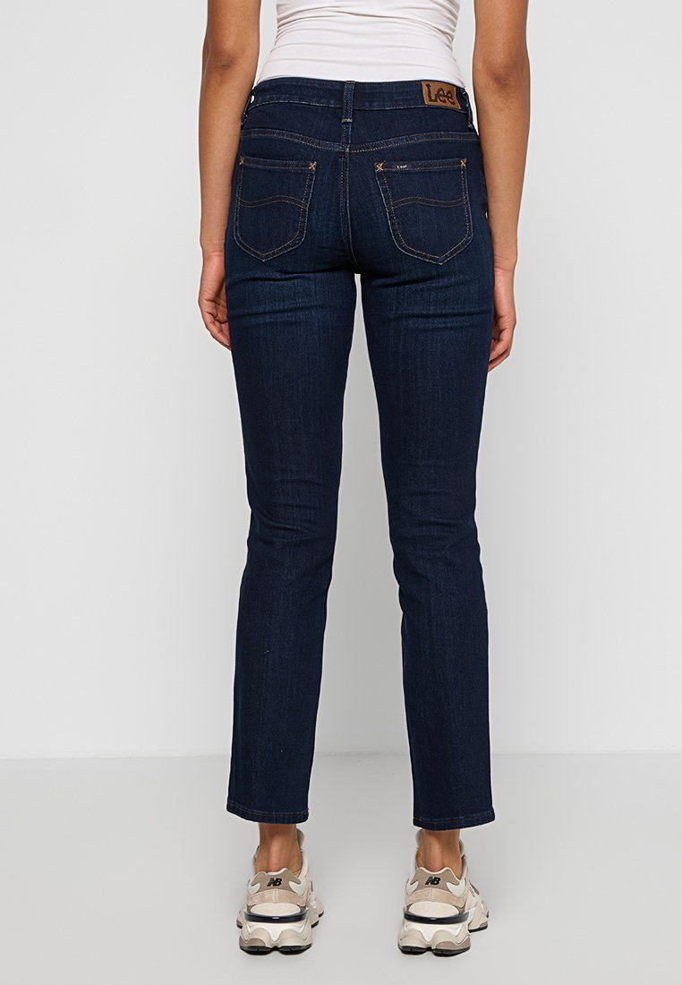 Jeans in denim blu scuro con vestibilità slim, dotati di due tasche posteriori, cuciture a contrasto e un'etichetta in pelle marrone in vita.