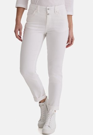 Schmal geschnittene weiße Jeans mit aufgerollten Bündchen, getragen mit weißen High-Top-Sneakers und einem weißen Langarmoberteil.