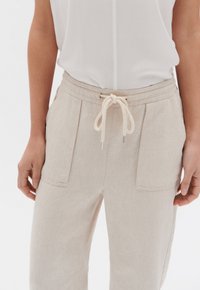 Beige linnen broek met een koordje in de taille, voorzien van twee voorzakken en een ontspannen pasvorm. Zachte textuur en eenvoudige designdetails.