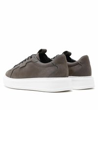 Sneakers in suede grigio con suola in gomma bianca, caratterizzati da un design a profilo basso, lacci neri e un tassello sul tallone.