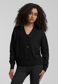 Zwarte gebreide cardigan met een v-hals, knopen aan de voorkant en geribde manchetten en zoom. Zachte textuur, casual pasvorm en lange mouwen.