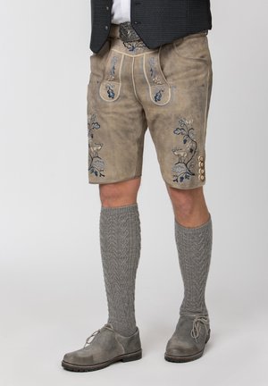 Traditionelle beige Lederlederhosen mit blau-weißer Stickerei, graue gestrickte knielange Socken und graue Leder-Schnürschuhe.