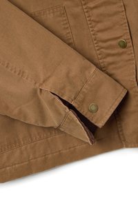 Braune Baumwolljacke mit einem Knopfverschluss an den Ärmeln, mit einer glatten Textur, sichtbaren Nähten und einem seitlichen Schlitz für Bewegungsfreiheit.