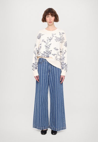 Cream sweater with blue floral print, oversized fit. Light blue wide-leg striped denim pants. Black shoes.