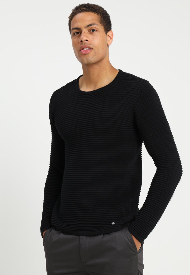 Black long-sleeve knit sweater featuring a textured ribbed design, round neckline, and a slim fit. Includes a subtle logo detail.