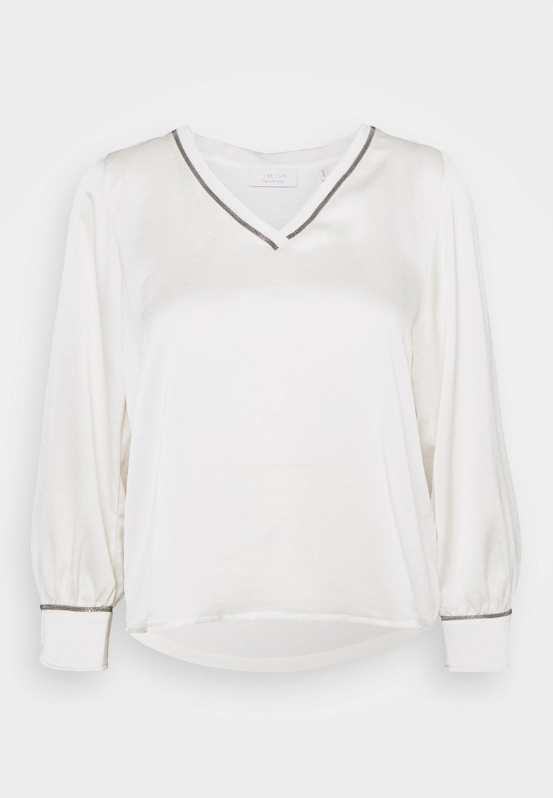 Blouse blanche à manches longues avec décolleté en V et bordure argentée sur le col et les poignets, avec des manches légèrement bouffantes et un ourlet incurvé.