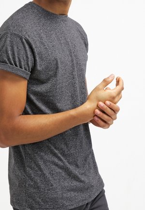 T-shirt gris à manches courtes avec un motif texturé. Encolure ronde et manches retroussées. Le tissu semble doux et décontracté.