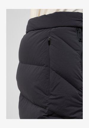 Schwarzer Puffrock mit gesteppter Optik, Reißverschlusstasche und elastischem Bund. Das Material hat eine glatte, matte Textur.