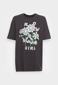 Černé bavlněné tričko s barevným květinovým motivem a usmívajícími se obličeji s nápisem "GROW YOU GIRL." Volný střih s krátkými rukávy.