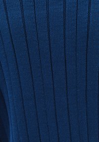 Sininen neulottu villapaita, jossa pystysuora ribbineulos, sileä pinta ja tasaiset ompeleet korostavat vaatteen joustavuutta ja muotoilua.