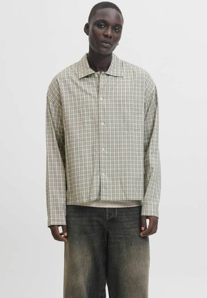 Lettet, ternet skjorte med knapper i grønne, brune og hvide nuancer, med en afslappet pasform og en brystlomme. Båret over mørk denim.