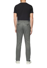 Pantalons habillés texturés gris avec deux poches arrière et des accents de boutons noirs, associés à un t-shirt noir ajusté et des baskets blanches.