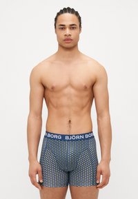 Herren Boxer-Shorts aus navyblauem Stoff mit geometrischem Muster. Verfügt über einen elastischen Bund mit Markenlogo und ein enganliegendes Design.
