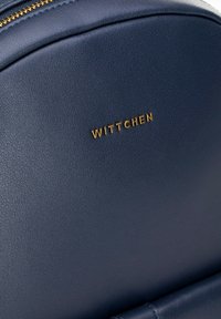 Granatowy skórzany plecak o teksturowanej powierzchni, z złotym logo "WITTCHEN" i gładkim zamkiem u góry.