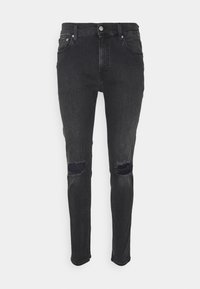 Jeans de mezclilla negra con corte ajustado, que presentan agujeros desgastados en las rodillas, diseño clásico de cinco bolsillos y herrajes de botón metálico. Textura suave.