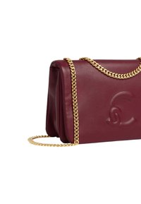 Borsa a mano in pelle color bordeaux con tracolla a catena dorata e dettaglio logo in rilievo. Caratterizzata da un design strutturato e una texture liscia.