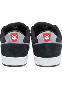 Sorte mokasiner i semsket skinn med et grått semsket panell, hvit gummisåle og en rød logo-patch på hælen. Teksturert, lavt design.